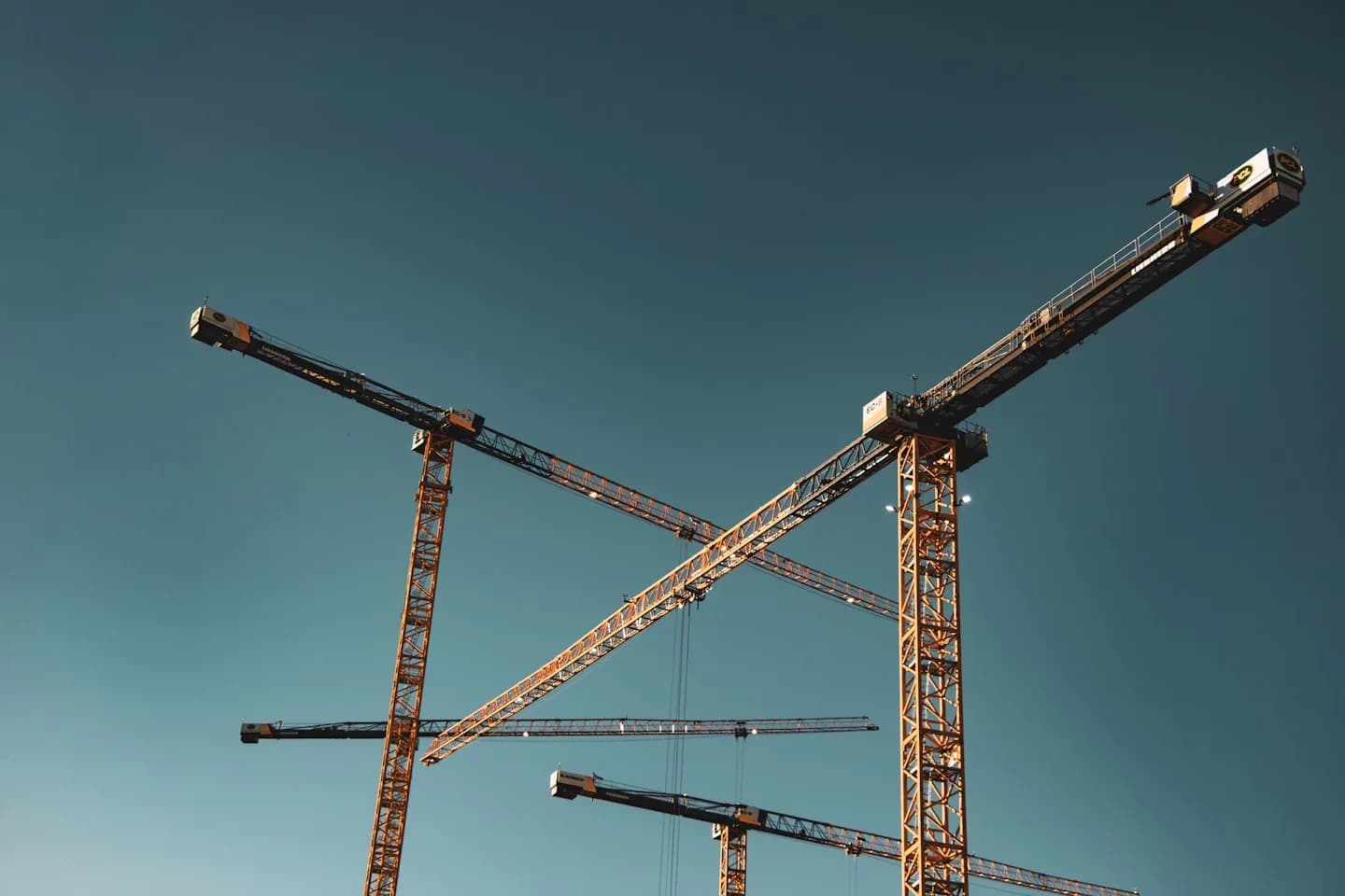 Construction cranes and buildings beneath a clear sky
